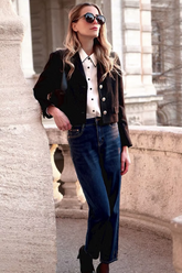 a lady in a white shirt, a black knit top and a pair of blue jeans